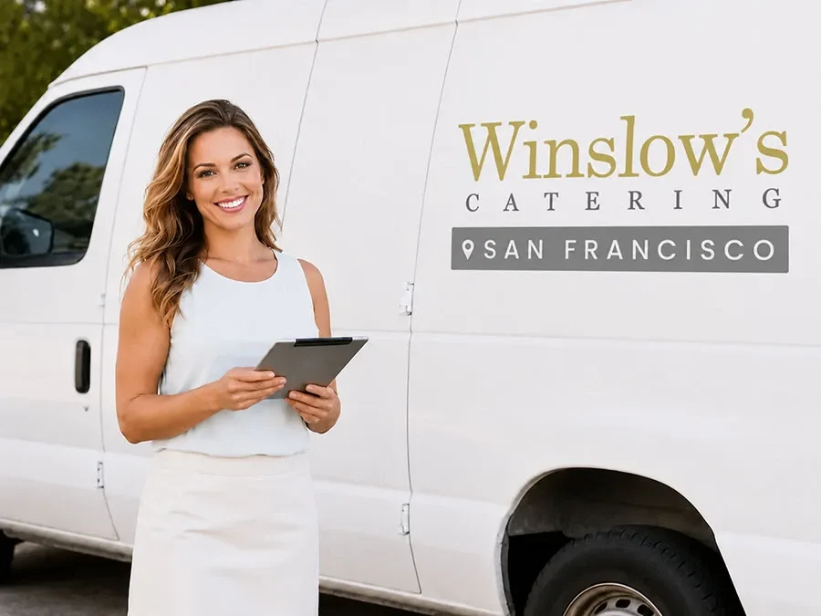 Winslow's catering coordinator checking a delivery order beside the branded white van before an office lunch drop-off in San Francisco